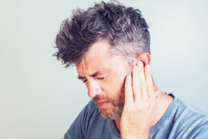 Man with earache is holding his aching ear body pain